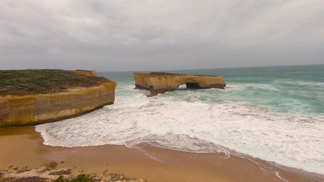 London Arch attraction, Great Ocean Road, Melbourne, Australia. Loch Ard Gorge. Dramatic coastal rock cliff edge, with ocean waves through bay. Sand, sea, holiday, vacation concepts. 4K.