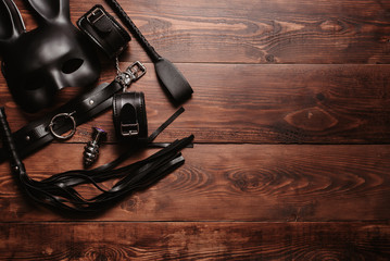 Set of erotic toys for BDSM sex. Lash, handcuffs, leather belt, mask and a plug