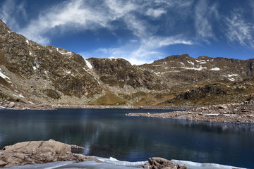 Lake surrounded by mountains and sky with clouds