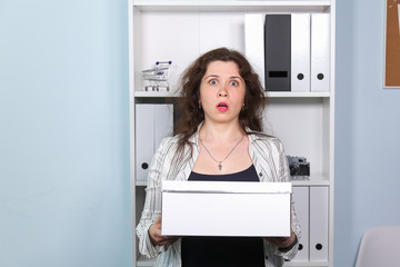 Concept of dismissal from work. Stunned woman with carton box with her stationery stuff, girl was fired from her job.