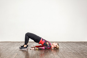 Athletic woman in tight sportswear practicing yoga, doing bridge pose bending back, stretching...