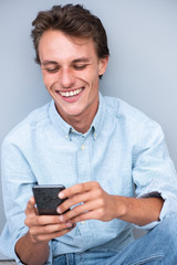 smiling young man sitting and looking at cellphone