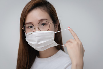 Asian Young woman in a white t-shirt and wear a medical mask that protects against the spread of coronavirus or COVID-19 disease. Studio Portrait with White Background. 