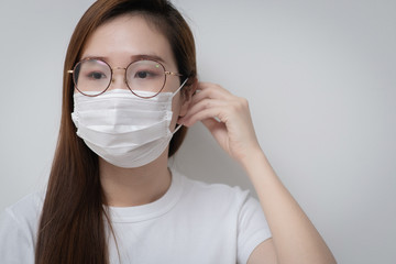 Asian Young woman in a white t-shirt and wear a medical mask that protects against the spread of coronavirus or COVID-19 disease. Studio Portrait with White Background. 