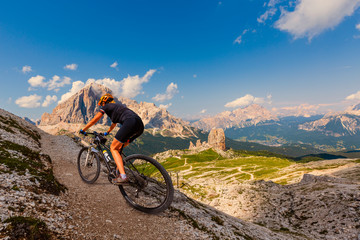 Cycling outdoor adventure in Dolomites. Cycling woman in Dolomites landscape. Woman cycling MTB...
