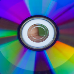 Compact Disc. Holding a CD in hands. The back side of the CD reflects colorful lights. Rainbow colors.