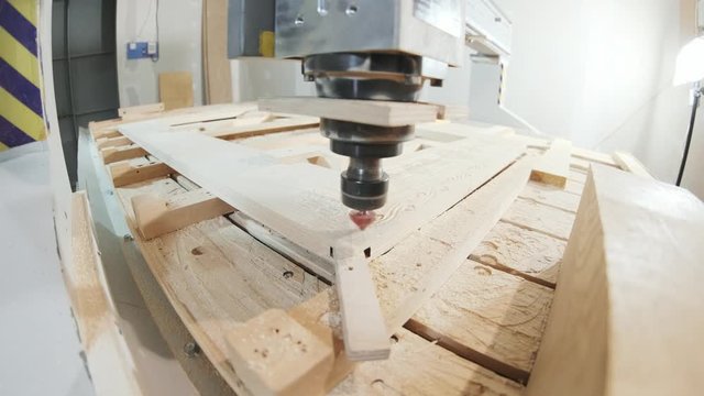 In the woodworkers shop the cnc drill is drilling a pattern in to the wooden plank, fish-eye shot