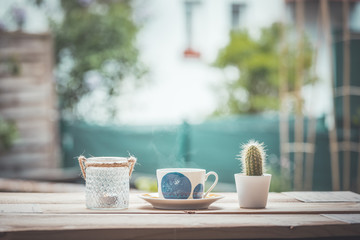 Garden enjoyment concept. Cup of tea, candle and plants on a rustic wooden table, leisure home