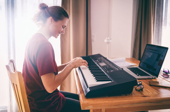 Young girl woman learns to sing and play the piano from a video conference from a laptop. Education video calls self education