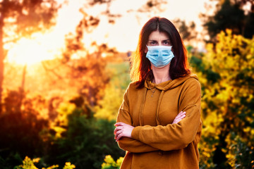 woman with face mask during coronavirus crisis in a natural environment - social distancing concept