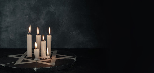 Six burning candles and the Star of David against on a dark gray background wall. - obrazy, fototapety, plakaty