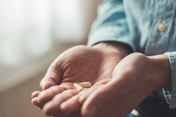 Medicament or cure concept. Close up of male hand with pills.