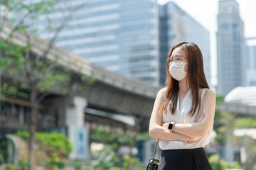 COVID-19 Pandemic Coronavirus Asian Woman in city street going to work. She wearing face mask protective for spreading of disease virus. 