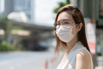 COVID-19 Pandemic Coronavirus Asian Woman in city street going to work. She wearing face mask protective for spreading of disease virus. 