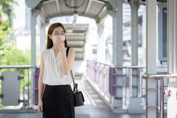 COVID-19 Pandemic Coronavirus Asian Woman in city street going to work. She wearing face mask protective for spreading of disease virus. 