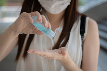 close up view of  Asian woman using small portable antibacterial hand sanitizer on hands for killing germs, bacteria, and viruses.