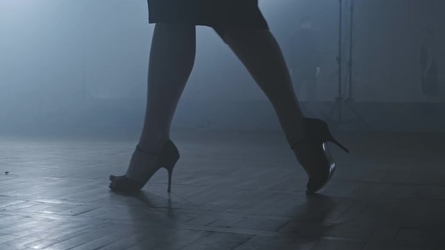 Legs of tango dancers in dark smoky studio. Woman goes to man. Woman legs on heels. Close-up shot in 4K, UHD
