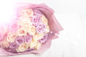 Bouquet of fresh amazing white and purple roses in craft paper on white background for postcard, cover, banner. Beautiful flowers as gift for Mother’s, Valentine’s Day, Birthday or Wedding. Copy space