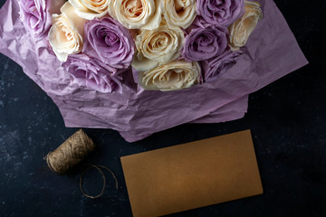 Bouquet of fresh amazing white and purple roses and craft envelope. Gift for holiday Mother's, Valentine's day, birthday, anniversary and Wedding. Gift Wrapping Concept. Copy space for text.