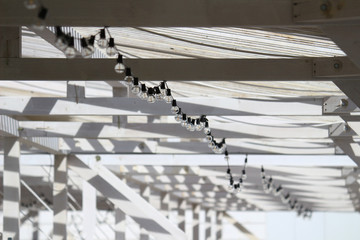 Fototapeta premium Abstract concept photo of a white beach house with vintage light bulbs decorated with cables that makes you feel summer
