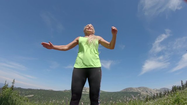 a happy young woman in leggings and a bright green t shirt jumps beautifully in the air against the background of a mountain valley. outdoor fitness, Sports and healthy lifestyle. Pretty fit girl