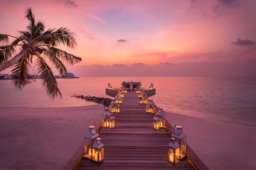 Foto auf Acrylglas Romantic dinner on the beach with sunset, candles with palm leaves and sunset sky and sea. Amazing view, honeymoon or anniversary dinner landscape. Exotic island evening horizon, romance for a couple  © icemanphotos