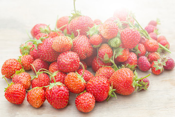 Natural organic food production. Freshly picked juicy strawberries on wooden background. Heap of summer red berries. Homegrown, gardening and agriculture consept. Backlight