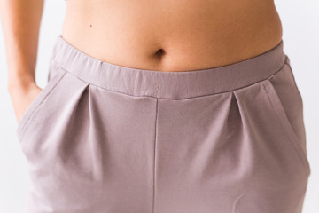 Close up photo of female slim belly with purple pants.