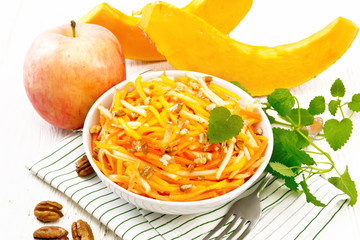 Salad of pumpkin and apple in bowl on board