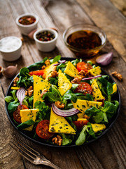 Fresh salad - blue cheese, cherry tomatoes, vegetables and walnuts on wooden background
