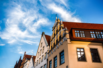 Obraz premium Beautiful old buildings against blue summer sky in Luneburg, Germany. Roofs of traditional old houses in historical center of the city. Travel vacation concept