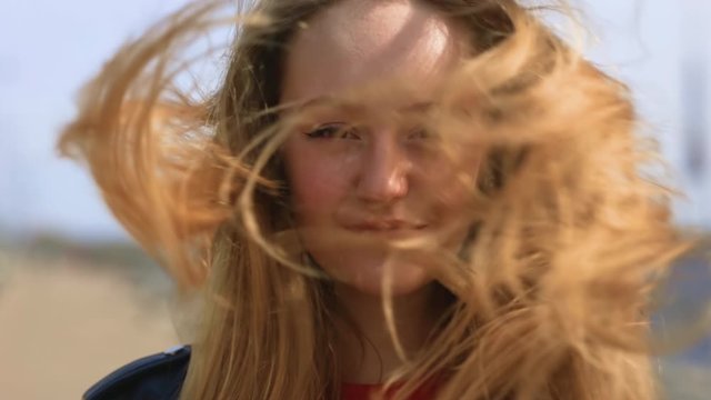 Young blonde woman looks at you in windy weather