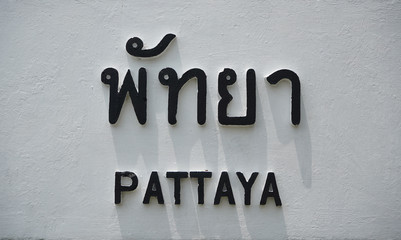 Pattaya wordings both Thai and English are painted in Black on white cement background.  Text, ...