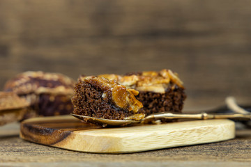 Close up toffee cake on steel spoon and on wooden background.