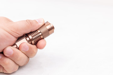 Metal flashlight in the hand with copy space above white background