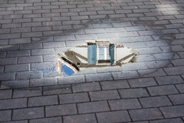 View of traditiobal architecture in the reflect of the puddle of water in Mulhouse - France