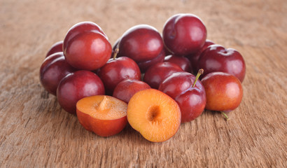 Bright red plums on old wood background