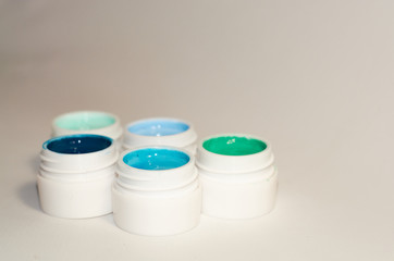 On white background cans with different shades of blue color with paints, varnishes for manicure.