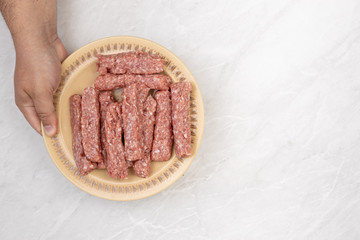 Top view of raw minced meat kebabs on the plate