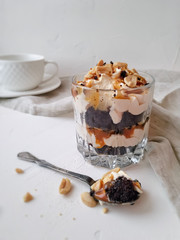 Chocolate dessert with salted caramel and peanuts in a glass close-up on a light background.