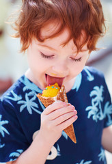 happy redhead boy eating an ice cream in a cone