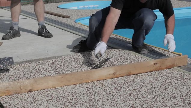 Laying the floor around the outdoor pool. The worker places a stone carpet with resin.
(Shallow DOF).