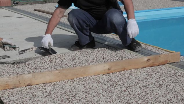 Laying the floor around the outdoor pool. The worker places a stone carpet with resin.
(Shallow DOF).