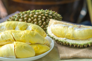 Close up delicious golden durian (Monthong) on white plate and peeling durian on sack bag and wood...