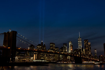 Fototapeta na wymiar Brooklyn Bridge in the night with Manhattan and the Twin Towers Tribute Lights at the background in 11S memorial day