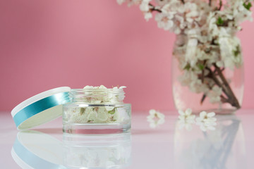 Concept natural organic cosmetics for skin care, spa and beauty. Flower and jar on pink background