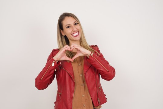 Beautiful caucasian woman over isolated background smiling in love showing heart symbol and shape with hands. Romantic concept.