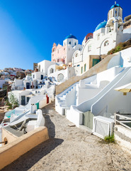 Oia typical architecture, Agios Spiridonas and Anastasi Church(blue dome), tower bell in the back, Santorini island, Cyclades, Greece
