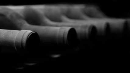 Dark and dusty wine bottles aging in a rack cellar with a perspective view.