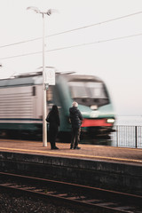 Two persons waiting the arriving train to stop in the platform.